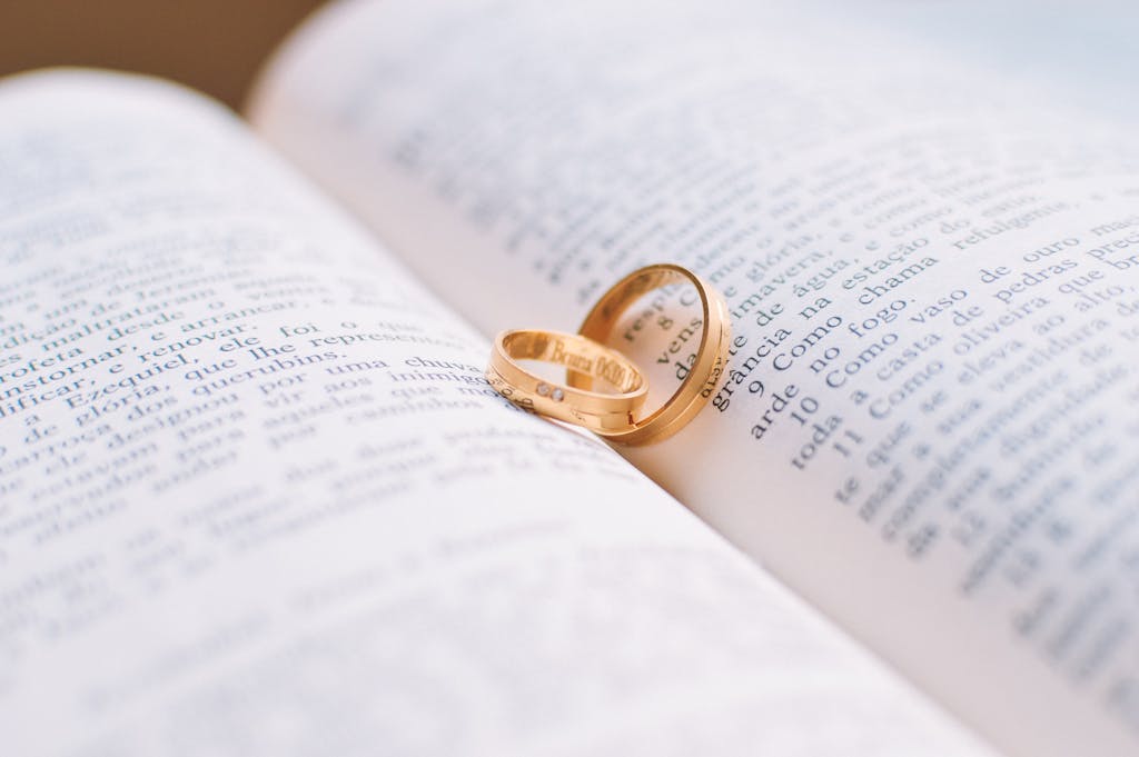 Close-up of wedding rings resting on the pages of an open book, symbolizing love and commitment.